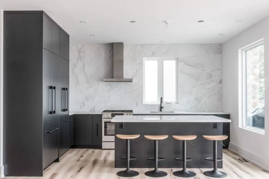 A kitchen with marble walls and black cabinets.