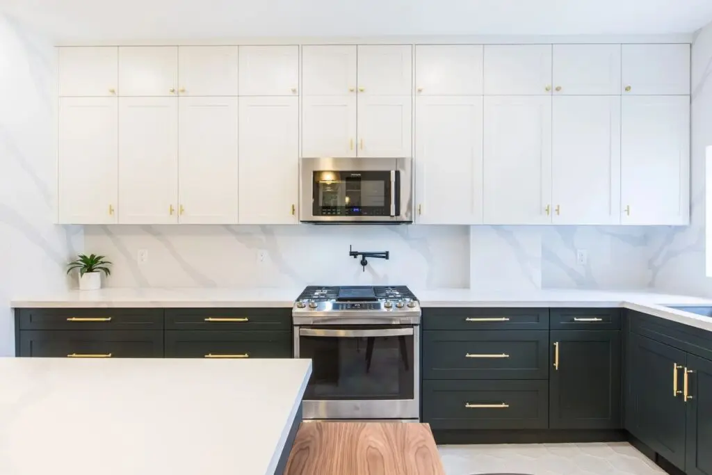 A kitchen with white cabinets and black drawers.