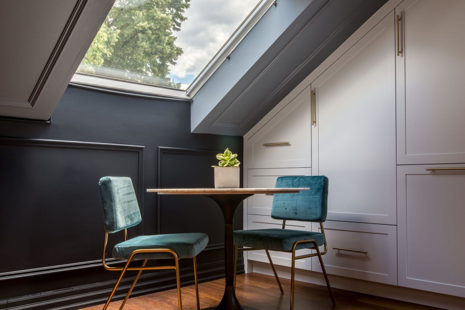 A table and two chairs in the corner of an attic room.