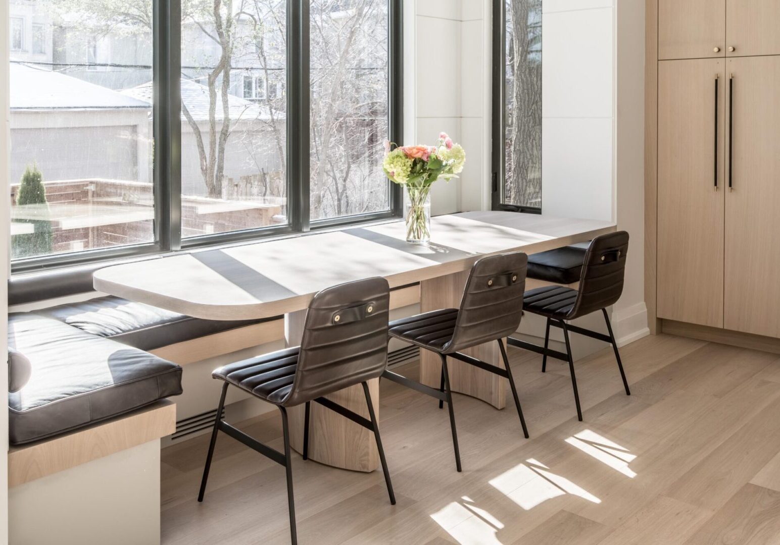 A dining room table with four chairs and a vase of flowers.