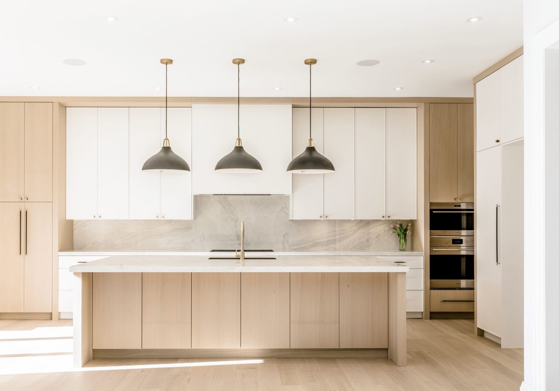 A kitchen with three lights hanging above the island.